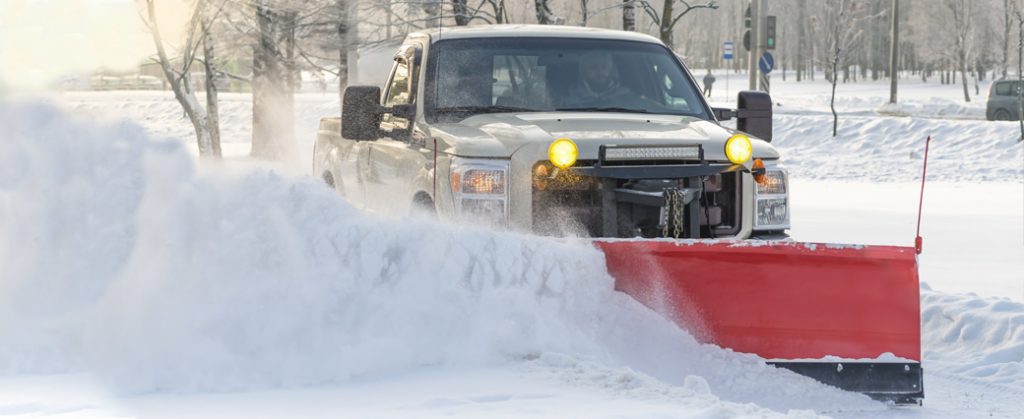 White pick up truck plowing snow